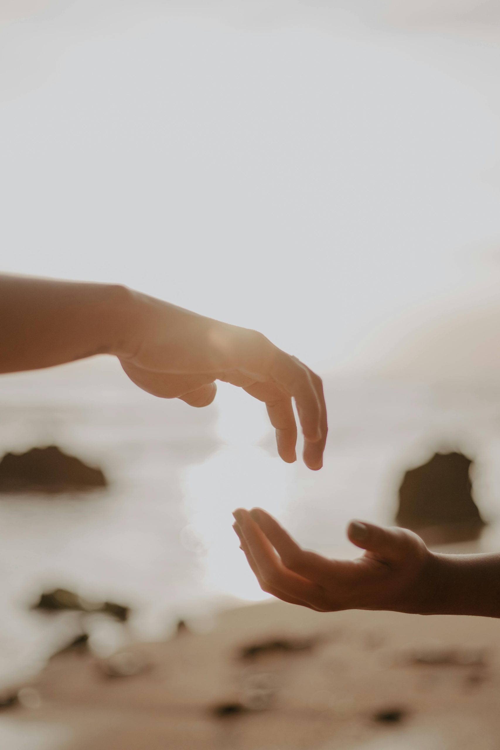 Hands Reaching Out in Sunlit Beach Setting